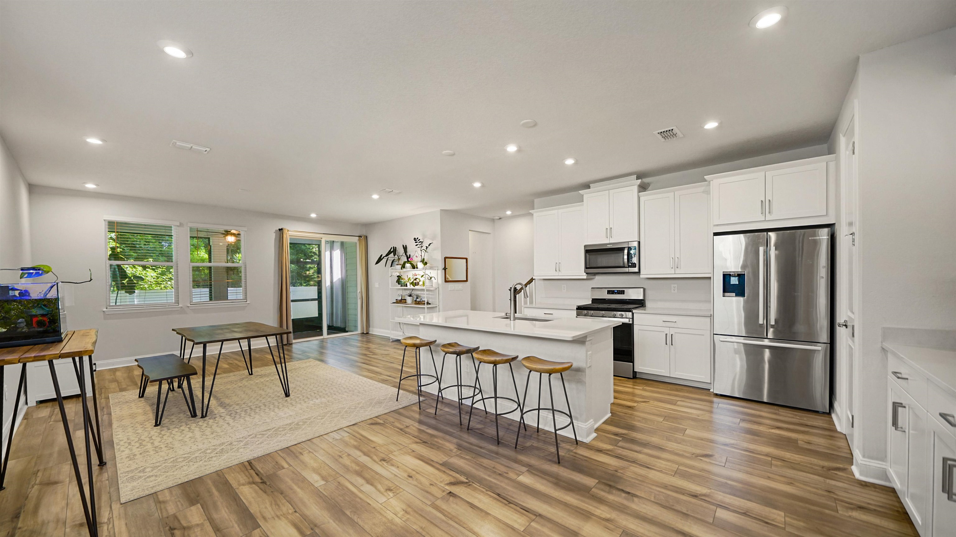 14141 Backbarrier Road Jacksonville, FL 32224 - Photo 2 of 45 a kitchen with stainless steel appliances kitchen island granite countertop a refrigerator a stove a dining table and chairs with wooden floor