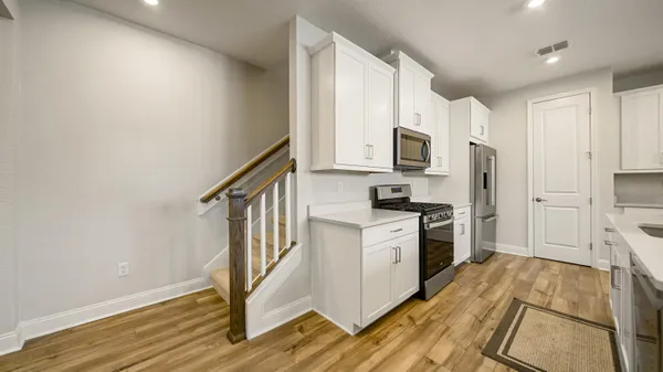 a kitchen with granite countertop a refrigerator a stove top oven and wooden floor