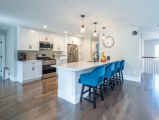 a large kitchen with cabinets wooden floor stainless steel appliances and dining table