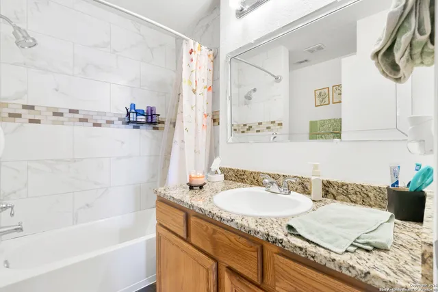 a bathroom with a granite countertop sink and a bathtub