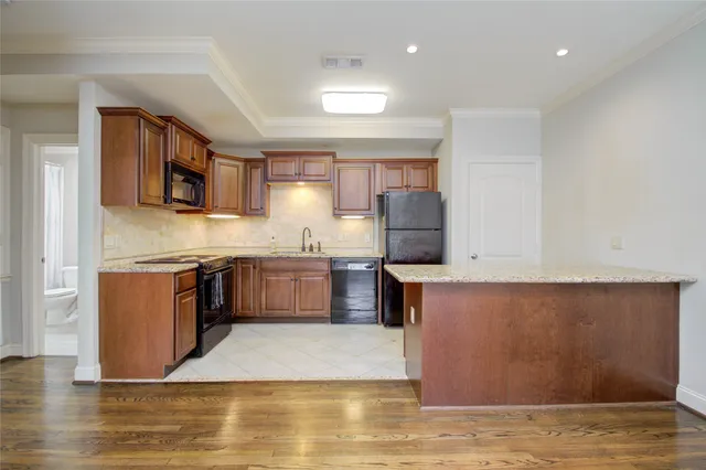 a large kitchen with stainless steel appliances granite countertop a stove a sink dishwasher a refrigerator and a oven with wooden floor