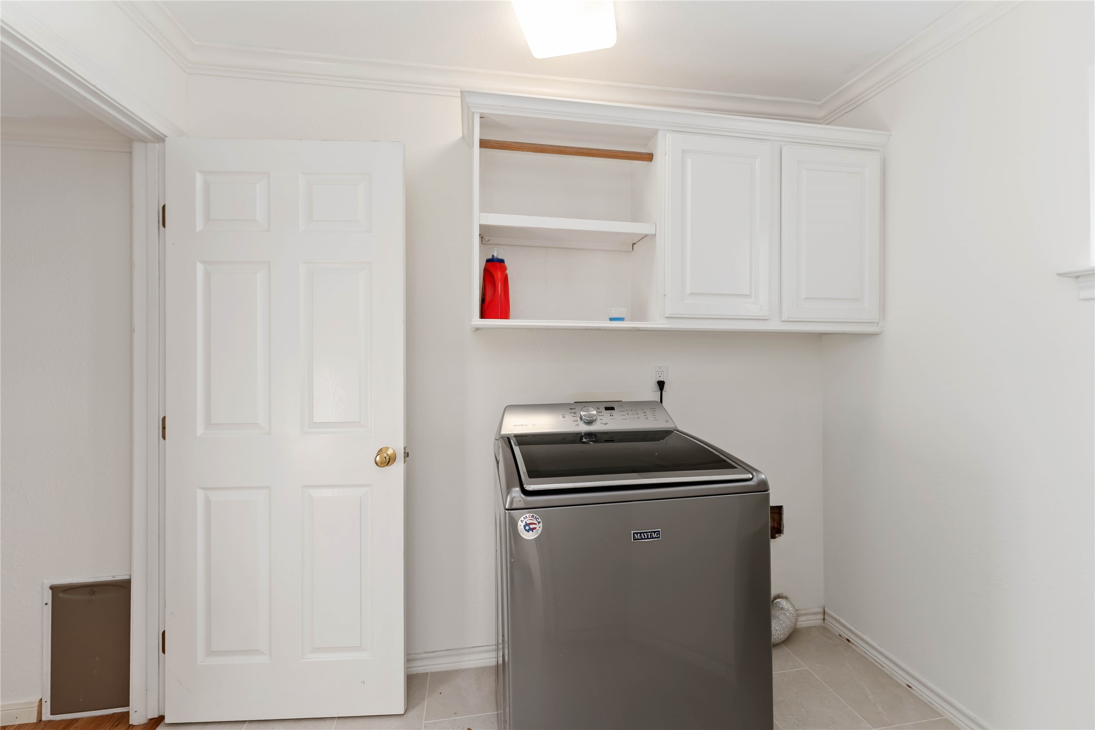 606 Packer Court Webster, TX 77598 - Photo 14 of 28 This laundry room has white walls and tiled flooring, with built-in white cabinets and helves for storage. There are doors leading to front hall and primary bathroom.