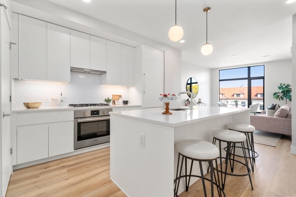 191 Washington Street, Unit 720 Boston, MA 02135 - Photo 4 of 29 a kitchen with stainless steel appliances a table and chairs in it
