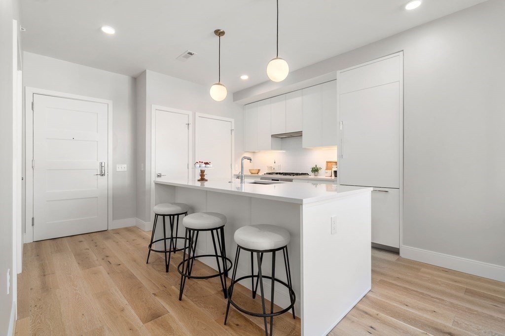 191 Washington Street, Unit 720 Boston, MA 02135 - Photo 5 of 29 a kitchen with kitchen island white cabinets and stainless steel appliances