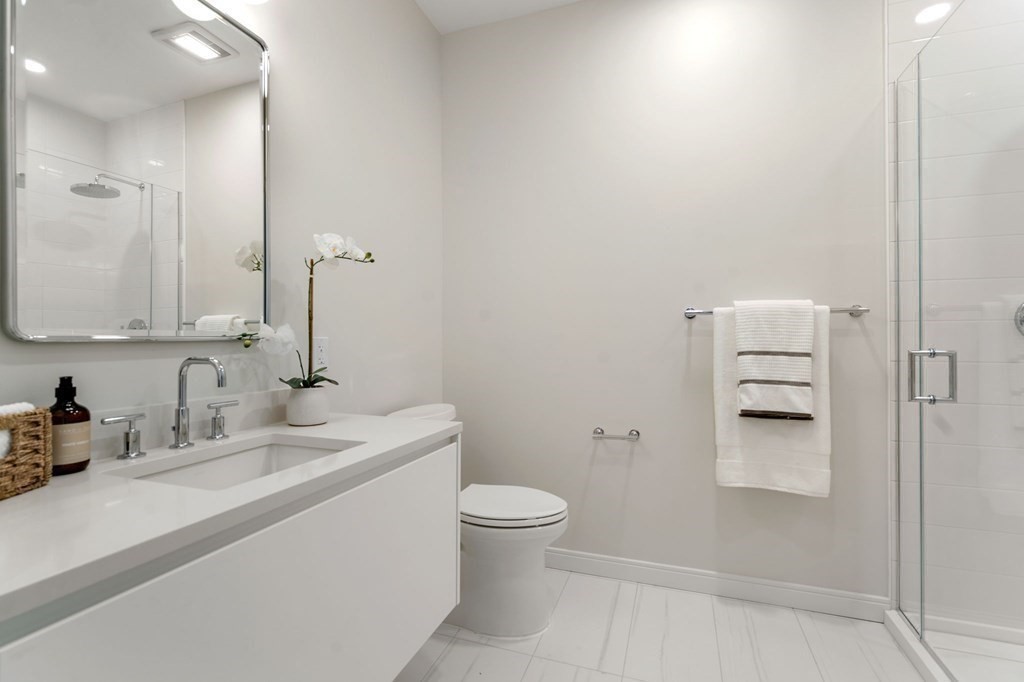 191 Washington Street, Unit 720 Boston, MA 02135 - Photo 9 of 29 a bathroom with a sink a toilet and a mirror