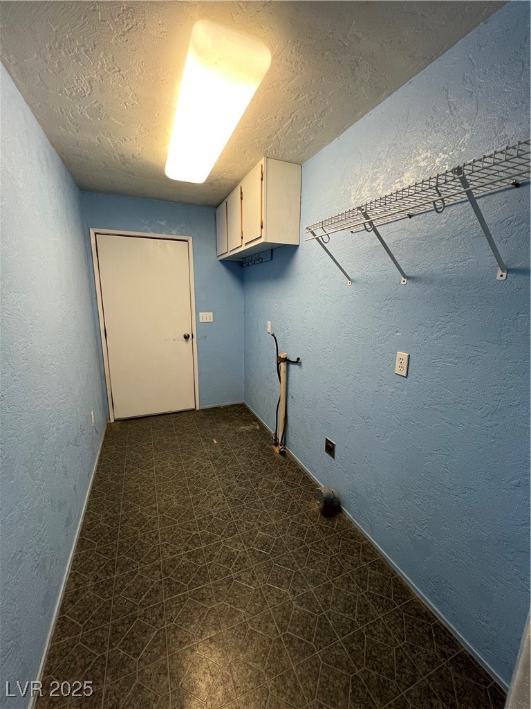 2151 West Simkins Road Pahrump, NV 89060 - Photo 23 of 23 Laundry room with a textured wall, a textured ceiling, and cabinet space