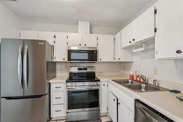 a kitchen with cabinets stainless steel appliances and sink