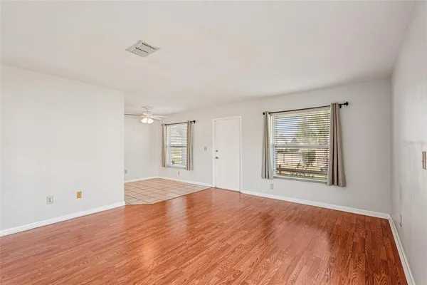 a view of empty room with wooden floor and fan