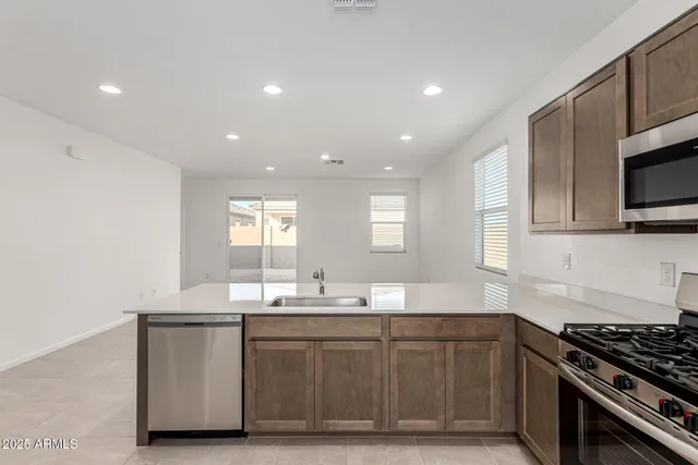 a kitchen with granite countertop a sink cabinets stainless steel appliances and a window