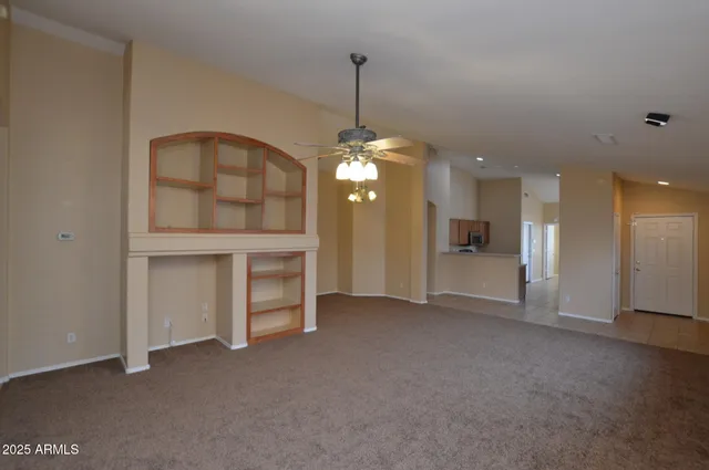 a view of an empty room with window and kitchen view