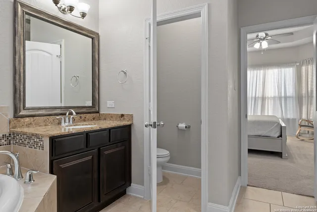 a en suite bathroom with a granite countertop sink and a mirror