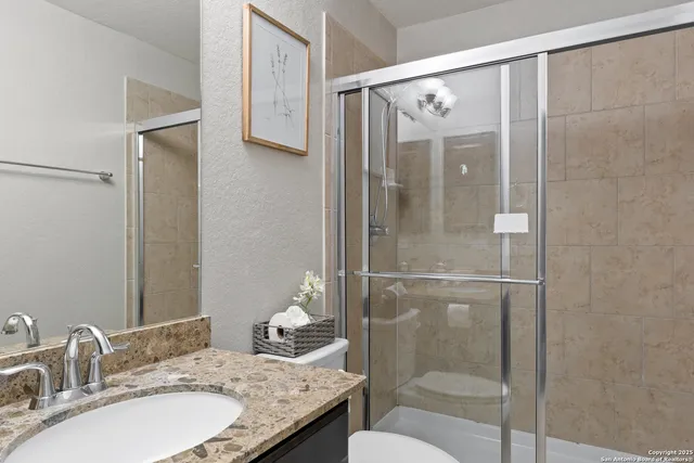 a bathroom with a granite countertop shower sink vanity and toilet