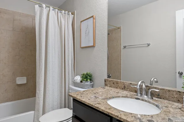 a bathroom with a granite countertop sink and a mirror with toilet