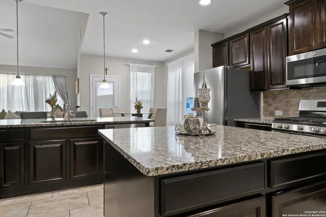 a kitchen with stainless steel appliances granite countertop a sink a stove and a refrigerator