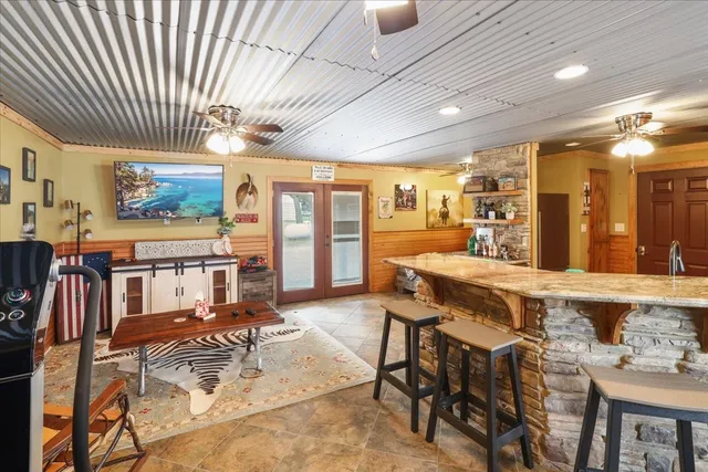 a living room with stainless steel appliances kitchen island granite countertop a refrigerator and a cabinets