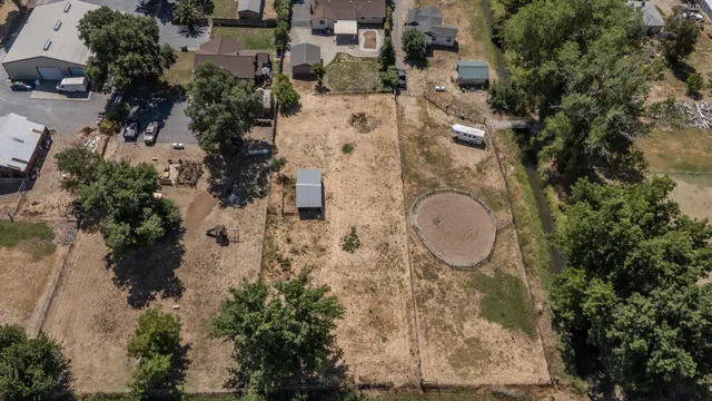 an aerial view of a house with a backyard space and trees all around