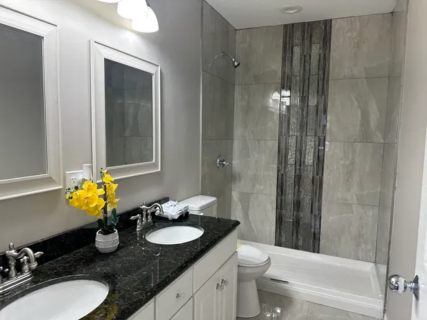 a bathroom with a granite countertop sink and a mirror with toilet