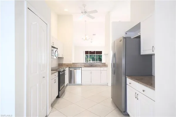 a kitchen with granite countertop white cabinets and appliances