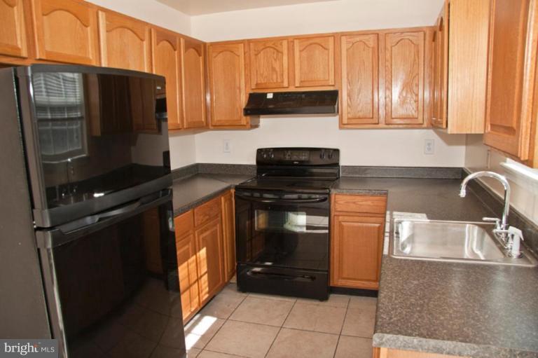 3515 Corn Stream Road Randallstown, MD 21133 - Photo 4 of 23 a kitchen with granite countertop a refrigerator and a stove top oven