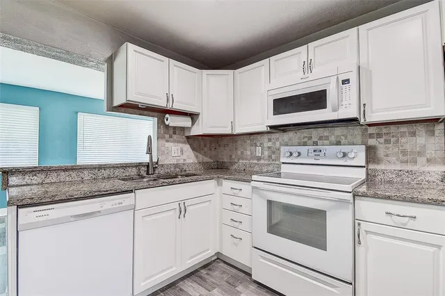 a kitchen with granite countertop white cabinets and sink