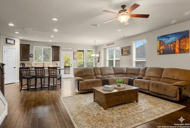 a kitchen with stainless steel appliances kitchen island granite countertop a refrigerator a stove a sink a dining table and chairs with wooden floor