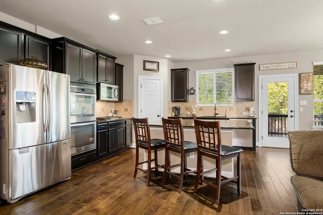 a kitchen with stainless steel appliances granite countertop a sink a stove and a refrigerator