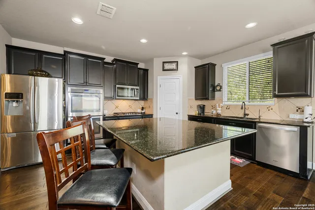 a kitchen with stainless steel appliances kitchen island granite countertop a stove and a sink