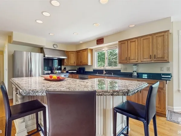a kitchen with stainless steel appliances granite countertop a table chairs sink refrigerator and cabinets