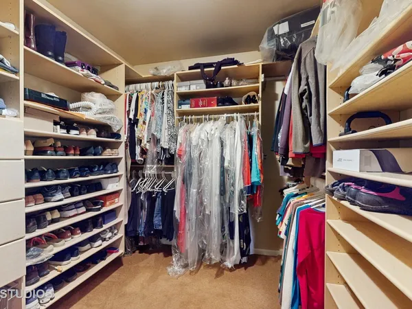 a view of walk in closet with clothes and shoes