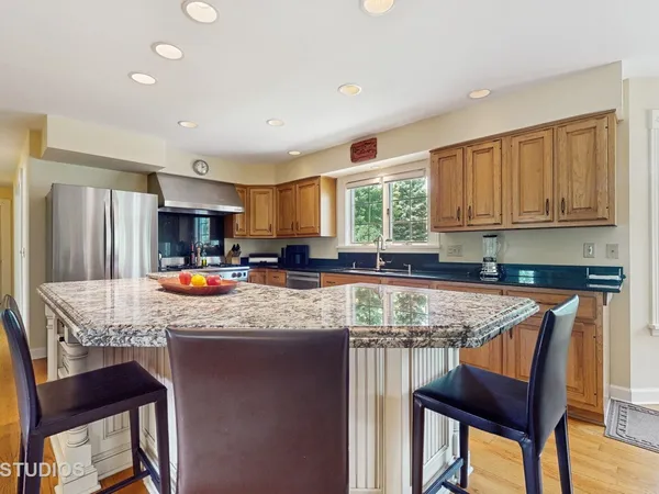 a kitchen with stainless steel appliances granite countertop a table chairs sink refrigerator and cabinets