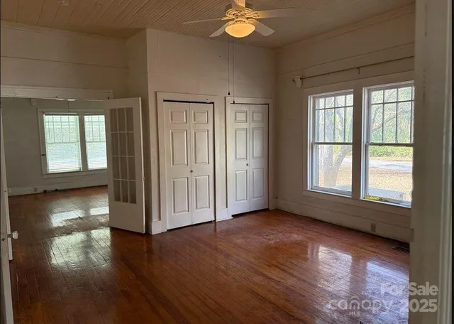 an empty room with wooden floor and windows