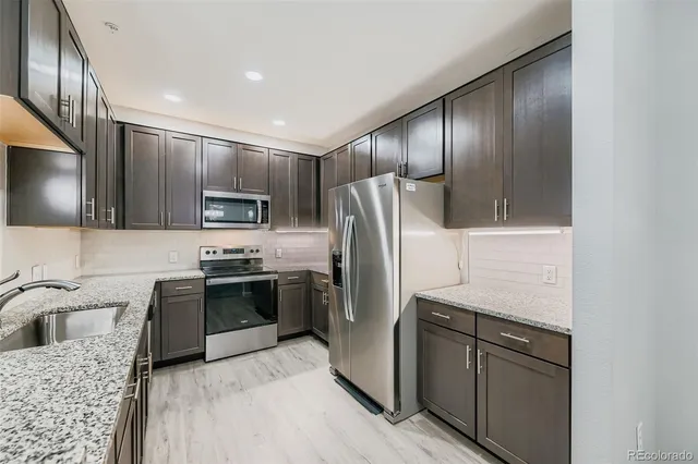 a kitchen with stainless steel appliances granite countertop a refrigerator stove and sink