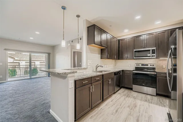 a kitchen with stainless steel appliances granite countertop a stove top oven a sink dishwasher a refrigerator and a refrigerator with wooden floor