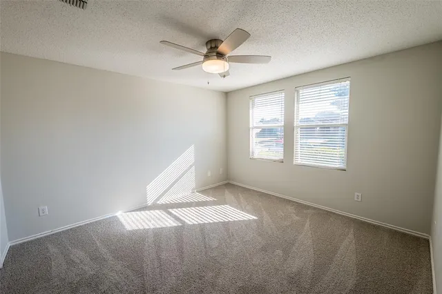 an empty room with windows and ceiling fan