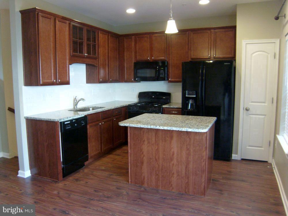 3784 William Daves Road, Unit 12 Doylestown, PA 18902 - Photo 6 of 19 a kitchen with stainless steel appliances granite countertop wooden cabinets a refrigerator a sink a stove a microwave and wooden floors