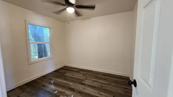 a view of an empty room with wooden floor and a window