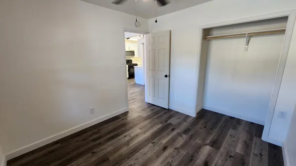 a view of an empty room with wooden floor and closet
