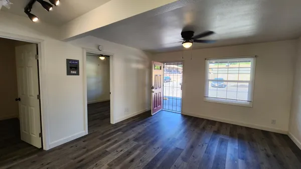 a view of an empty room with wooden floor and a window