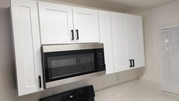 a view of an empty room with wooden floor and a cabinet