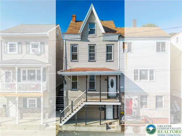 a view of a white house with large windows and a small yard