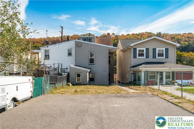 a view of a white house with large windows next to a road