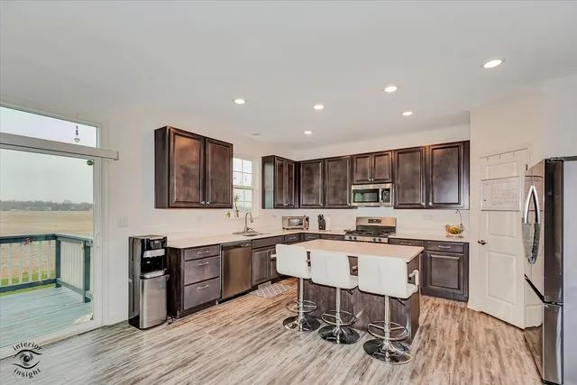 a kitchen with stainless steel appliances a dining table chairs microwave and sink