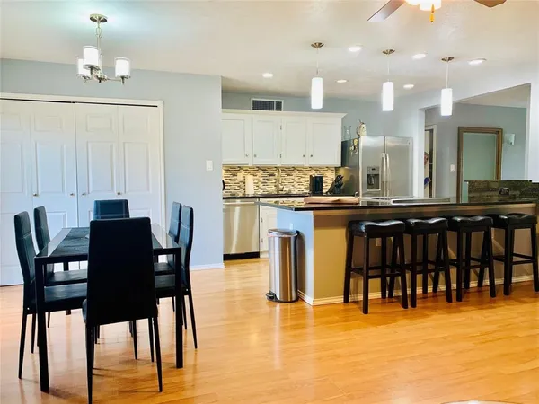 a kitchen with stainless steel appliances granite countertop table chairs and a living room view