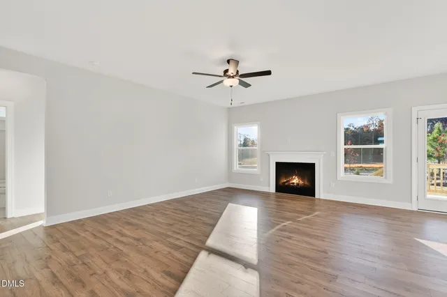 an empty room with fireplace chandelier fan and windows