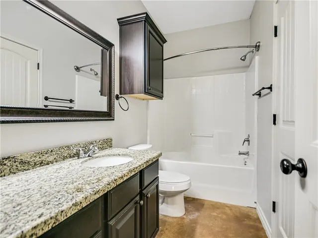 a bathroom with a granite countertop sink a toilet and shower