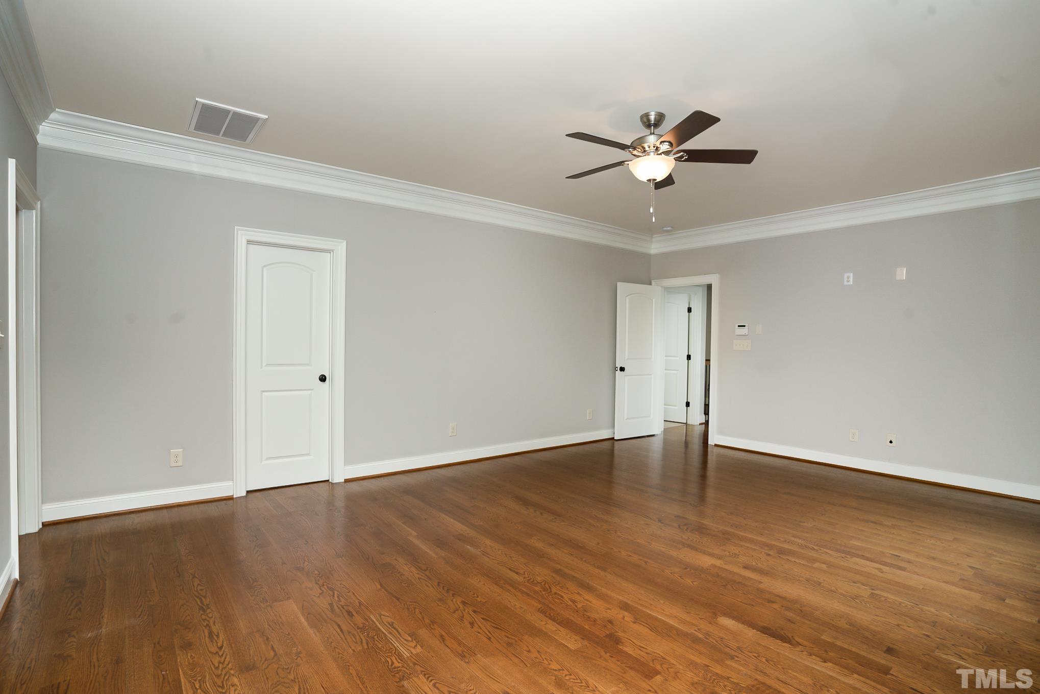5004 Greyhawk Place Apex, NC 27539 - Photo 14 of 36 an empty room with wooden floor a ceiling fan and closet