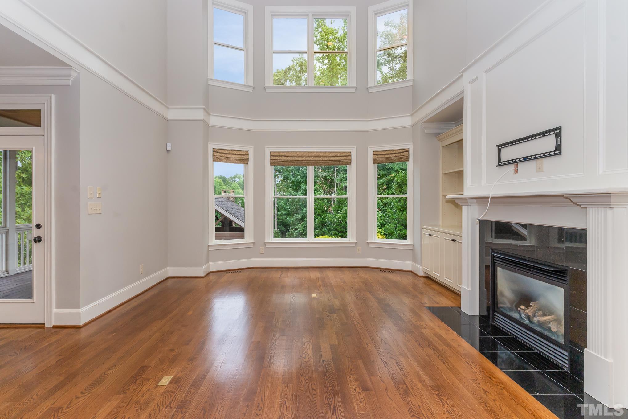 5004 Greyhawk Place Apex, NC 27539 - Photo 5 of 36 an empty room with wooden floor fireplace and windows