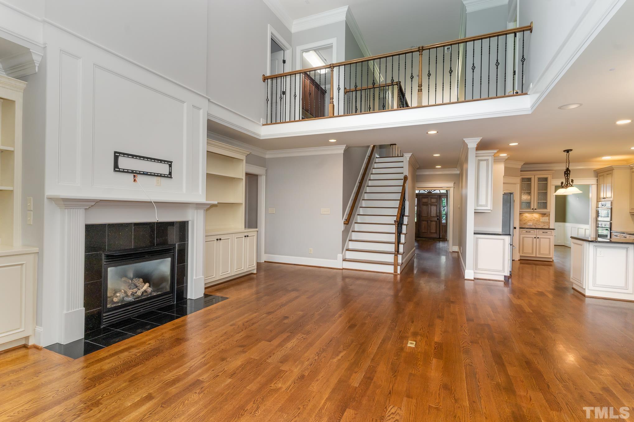 5004 Greyhawk Place Apex, NC 27539 - Photo 6 of 36 a view of a livingroom with wooden floor and a kitchen