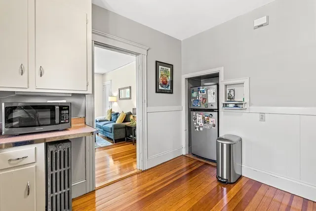 a living room with stainless steel appliances furniture a fireplace and a wooden floor