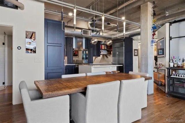 a living room with stainless steel appliances granite countertop a table chairs a flat screen tv and a refrigerator